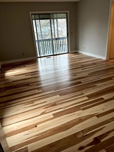 Natural finish hickory hardwood floor in a living room with a sliding glass door