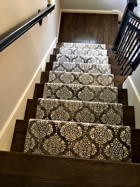 Damask-pattern stair carpet on a dark wood staircase, seen from the top