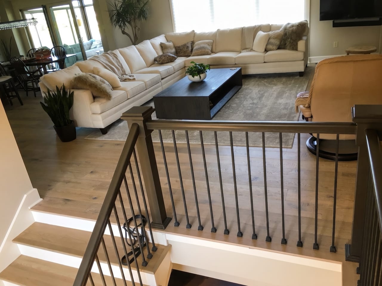 Open-plan living room with a wide-plank white oak floor running to a staircase with matching treads